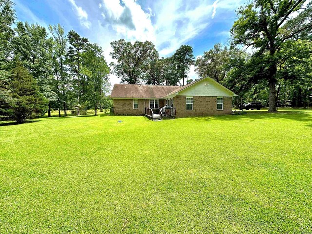 6823 Nevins Rd, Pine Bluff, AR 71603 - rear view of property with a lawn, brick siding, and view of wooded area