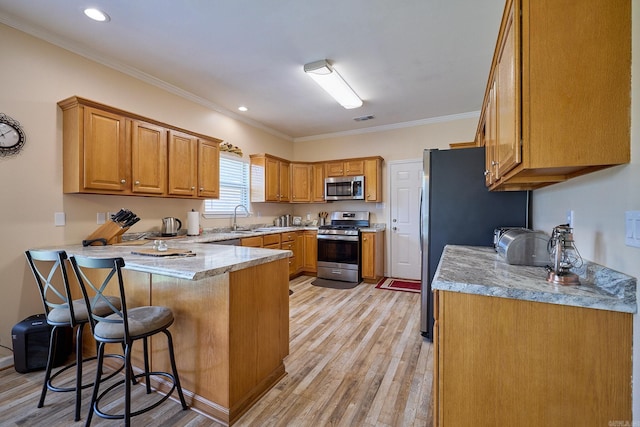 4116 Wildflower Ln, Benton, AR 72015 - kitchen featuring stainless steel appliances, a peninsula, a breakfast bar area, light wood finished floors, and crown molding