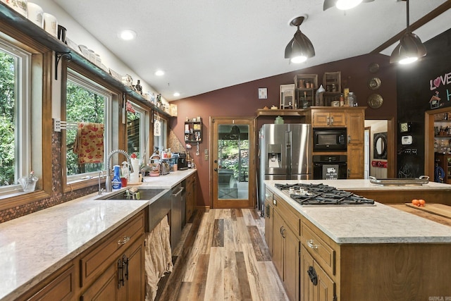 6307 Sunset Trl, North Little Rock, AR 72118 - kitchen featuring black appliances, lofted ceiling, light wood finished floors, estacked washer and dryer, and brown cabinetry