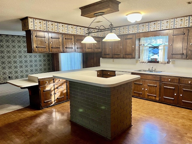 101 Fairway Dr, Bald Knob, AR 72010 - kitchen featuring wood finished floors, wallpapered walls, a textured ceiling, light countertops, and a center island