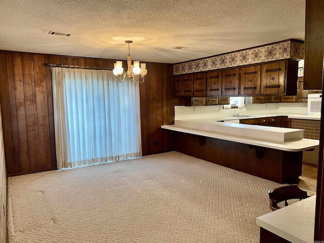 101 Fairway Dr, Bald Knob, AR 72010 - kitchen with light countertops, a textured ceiling, wood walls, a chandelier, and a kitchen breakfast bar