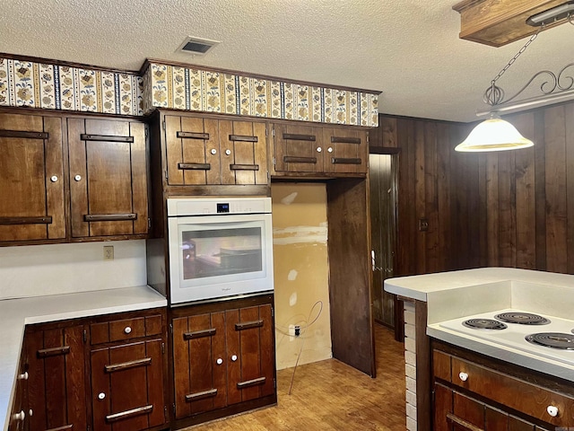 101 Fairway Dr, Bald Knob, AR 72010 - kitchen with white appliances, a textured ceiling, light countertops, light wood-style flooring, and decorative light fixtures