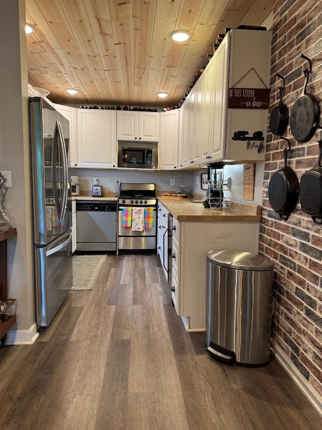 kitchen featuring appliances with stainless steel finishes, wooden ceiling, brick wall, dark wood-style floors, and white cabinets