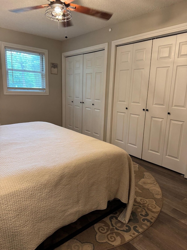 bedroom with dark wood-style floors, multiple closets, and ceiling fan