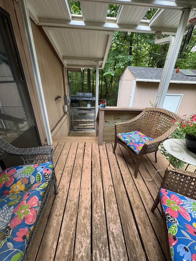 wooden terrace with a storage unit and area for grilling