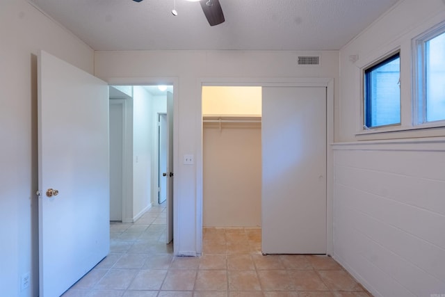 2128 Yamania Way, Heber Springs, AR 72543 - unfurnished bedroom with a closet, a walk in closet, light tile patterned floors, a ceiling fan, and a textured ceiling