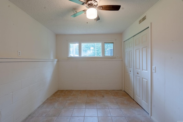 2128 Yamania Way, Heber Springs, AR 72543 - unfurnished bedroom with a textured ceiling, a closet, ceiling fan, and wainscoting