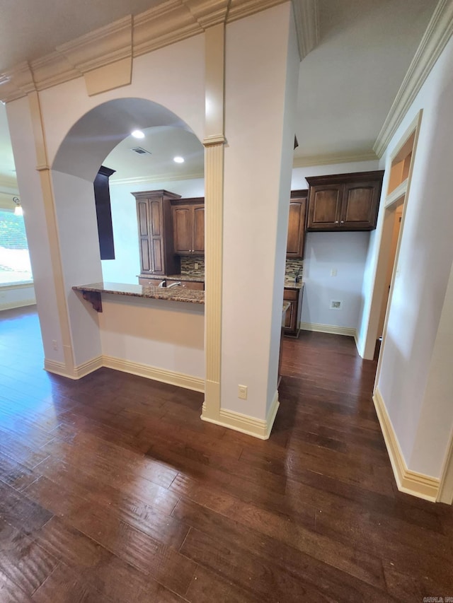 140 Bentley Cir, Little Rock, AR 72210 - kitchen with dark wood-style flooring, arched walkways, light stone counters, backsplash, and crown molding