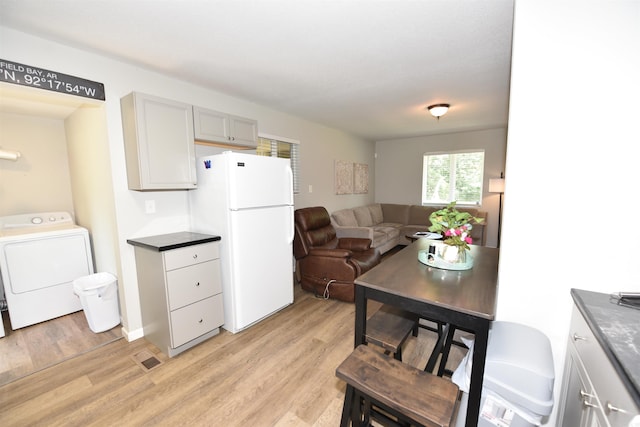 242 Lakeview Dr, Fairfield Bay, AR 72088 - kitchen with freestanding refrigerator, washer / dryer, light wood-style floors, dark countertops, and open floor plan