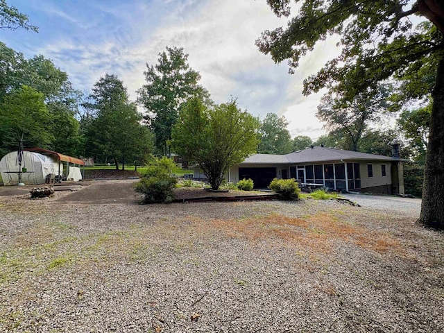 67 Powhatan Dr, Cherokee Village, AR 72529 - view of yard with an attached garage, driveway, a sunroom, and a storage unit