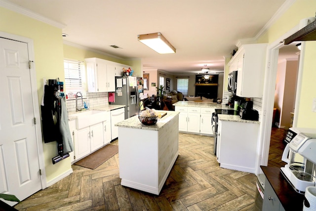 34 Ridge Rd, Cabot, AR 72023 - kitchen with appliances with stainless steel finishes, a center island, backsplash, white cabinetry, and crown molding