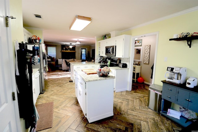 34 Ridge Rd, Cabot, AR 72023 - kitchen with stainless steel microwave, crown molding, white cabinetry, a center island, and light stone countertops