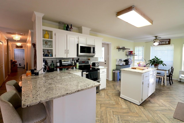 34 Ridge Rd, Cabot, AR 72023 - kitchen featuring appliances with stainless steel finishes, open shelves, white cabinetry, a kitchen breakfast bar, and crown molding