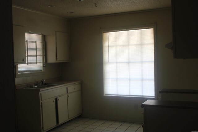 4406 W 16th Ave, Pine Bluff, AR 71603 - kitchen with white cabinets, light countertops, light tile patterned flooring, and a textured ceiling
