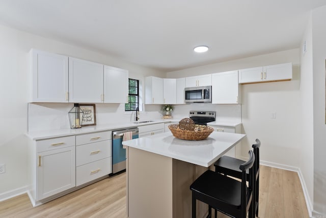 1495 Manor St, Conway, AR 72034 - kitchen with stainless steel appliances, white cabinets, backsplash, and light wood-style floors