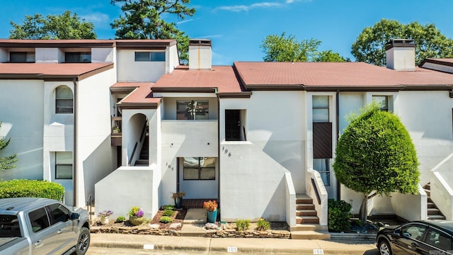 301 Kings Row Dr Unit 106, Little Rock, AR 72207 - view of property featuring a chimney, stairs, and stucco siding