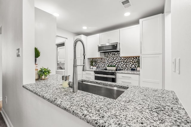 301 Kings Row Dr Unit 106, Little Rock, AR 72207 - kitchen with appliances with stainless steel finishes, light stone counters, tasteful backsplash, white cabinetry, and recessed lighting