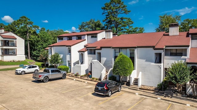 301 Kings Row Dr Unit 106, Little Rock, AR 72207 - view of front of home with uncovered parking, a chimney, and stucco siding