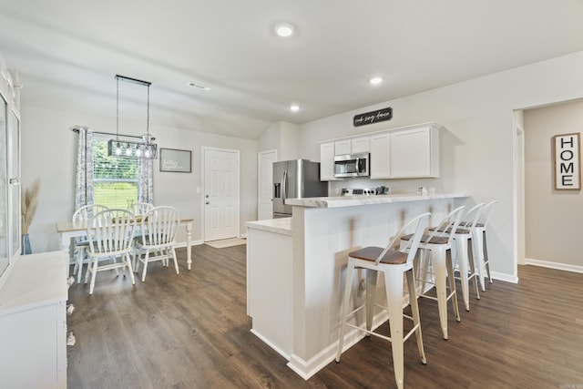 1040 Gallery Dr, Conway, AR 72032 - kitchen with stainless steel appliances, white cabinetry, dark wood finished floors, a kitchen bar, and recessed lighting
