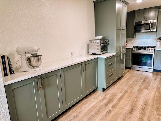 702 Polk Road 57, Mena, AR 71953 - kitchen with appliances with stainless steel finishes, light wood finished floors, light countertops, a textured wall, and green cabinets