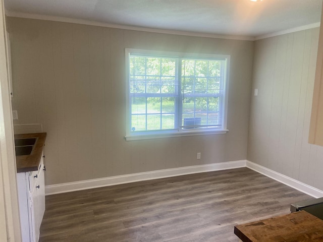 134 S Gosnell St, Gosnell, AR 72315 - unfurnished dining area featuring dark wood finished floors, crown molding, and wooden walls