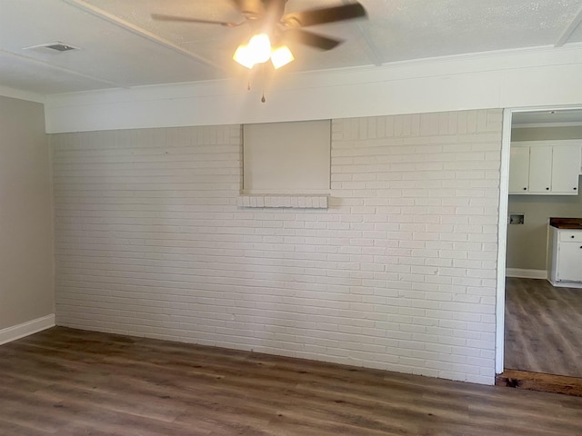 134 S Gosnell St, Gosnell, AR 72315 - unfurnished room featuring brick wall, dark wood-style flooring, ceiling fan, and crown molding