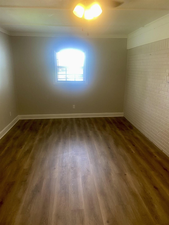 134 S Gosnell St, Gosnell, AR 72315 - empty room featuring brick wall, dark wood-type flooring, and crown molding