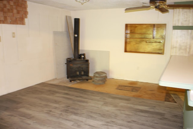 196 Stone Mountain Rd, Vilonia, AR 72032 - unfurnished living room featuring a ceiling fan, a wood stove, and wood finished floors