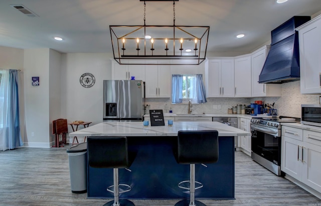226 Shamsie Ln, White Hall, AR 71602 - kitchen with appliances with stainless steel finishes, custom exhaust hood, backsplash, a kitchen island, and light wood-style floors