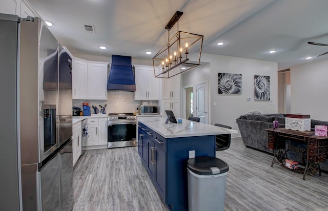 226 Shamsie Ln, White Hall, AR 71602 - kitchen featuring appliances with stainless steel finishes, custom range hood, blue cabinets, light wood-style floors, and recessed lighting