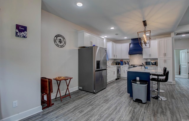 226 Shamsie Ln, White Hall, AR 71602 - kitchen featuring stainless steel appliances, premium range hood, wood finished floors, a kitchen bar, and decorative backsplash