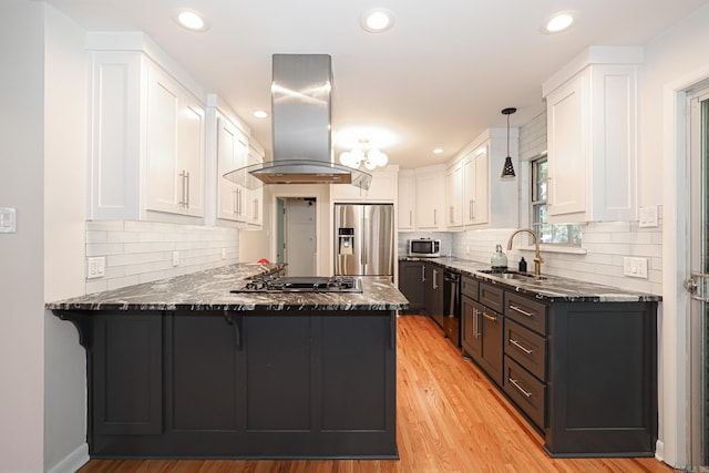 1913 Topf Rd, North Little Rock, AR 72116 - kitchen with stainless steel appliances, island exhaust hood, a peninsula, dark stone counters, and white cabinets