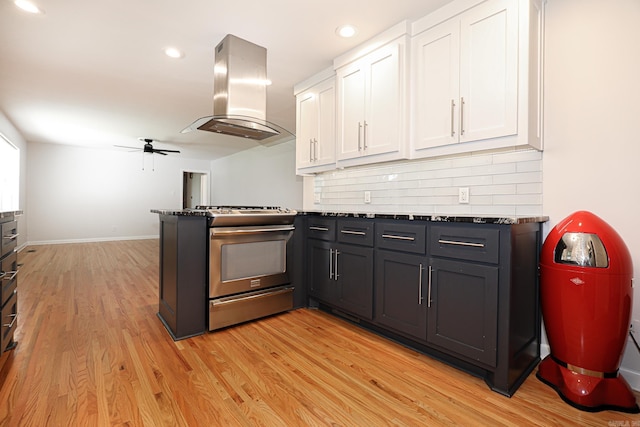 1913 Topf Rd, North Little Rock, AR 72116 - kitchen featuring stainless steel range with gas stovetop, island exhaust hood, white cabinetry, a peninsula, and ceiling fan