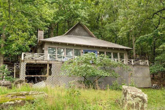 1032 Nunis Dr, Heber Springs, AR 72543 - rear view of property featuring a chimney, a wooden deck, a metal roof, and a forest view