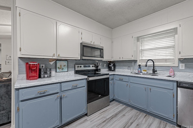 508 Cindy St, Paragould, AR 72450 - kitchen featuring stainless steel appliances, crown molding, blue cabinetry, a textured ceiling, and decorative backsplash