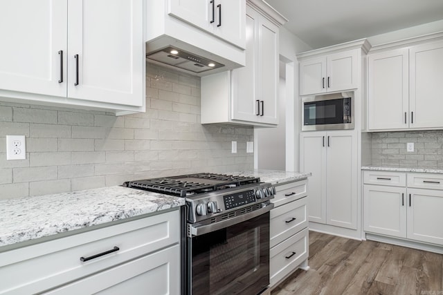 60 Estrella Way, Hot Springs Village, AR 71909 - kitchen featuring appliances with stainless steel finishes, backsplash, white cabinets, light wood-style flooring, and exhaust hood