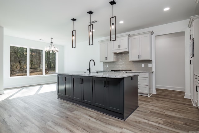 60 Estrella Way, Hot Springs Village, AR 71909 - kitchen with light wood-type flooring, a chandelier, decorative backsplash, light stone countertops, and recessed lighting