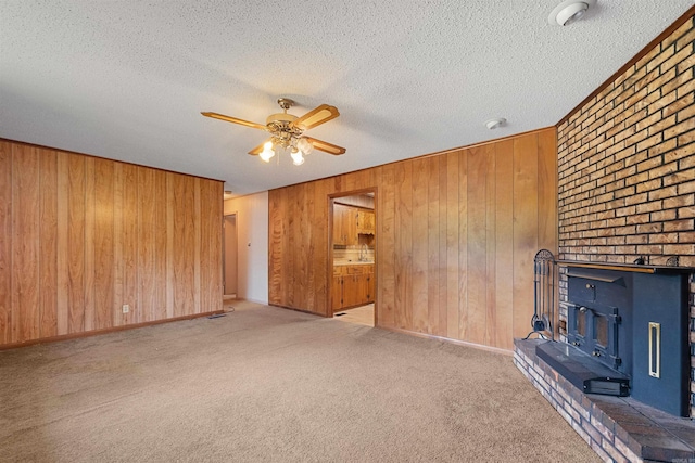 7025 Windsong, North Little Rock, AR 72113 - unfurnished living room with ceiling fan, wooden walls, carpet floors, a wood stove, and a textured ceiling
