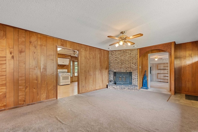 7025 Windsong, North Little Rock, AR 72113 - unfurnished living room featuring ceiling fan, wooden walls, a textured ceiling, carpet, and a fireplace