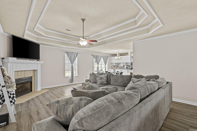 19 Mustang, Cabot, AR 72023 - living room with a tray ceiling, a tile fireplace, wood finished floors, ceiling fan, and ornamental molding