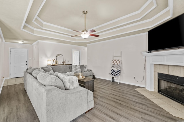 19 Mustang, Cabot, AR 72023 - living room with a tray ceiling, a tiled fireplace, ceiling fan, wood finished floors, and crown molding