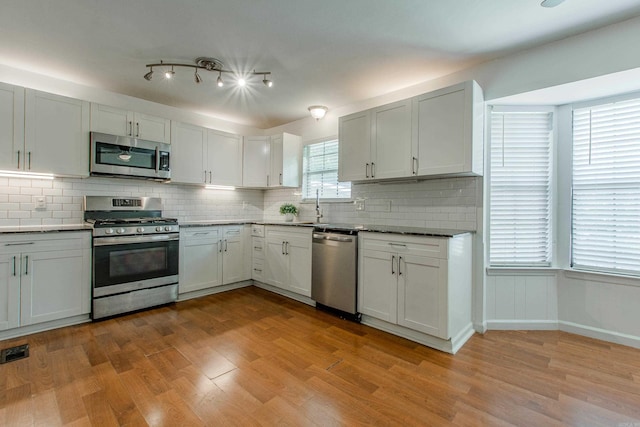 81 Stoneledge Dr, Maumelle, AR 72113 - kitchen featuring appliances with stainless steel finishes, decorative backsplash, wood finished floors, and white cabinets