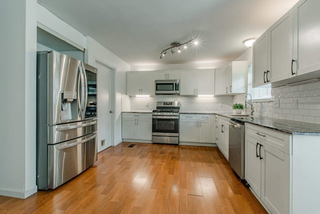 81 Stoneledge Dr, Maumelle, AR 72113 - kitchen featuring appliances with stainless steel finishes, backsplash, light wood finished floors, dark stone countertops, and white cabinets