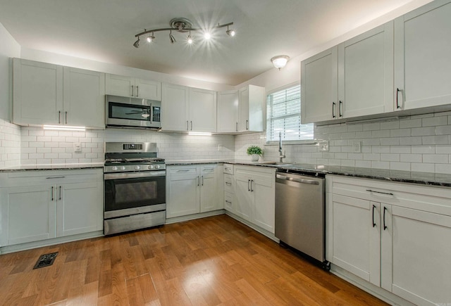 81 Stoneledge Dr, Maumelle, AR 72113 - kitchen featuring stainless steel appliances, decorative backsplash, dark stone countertops, and wood finished floors