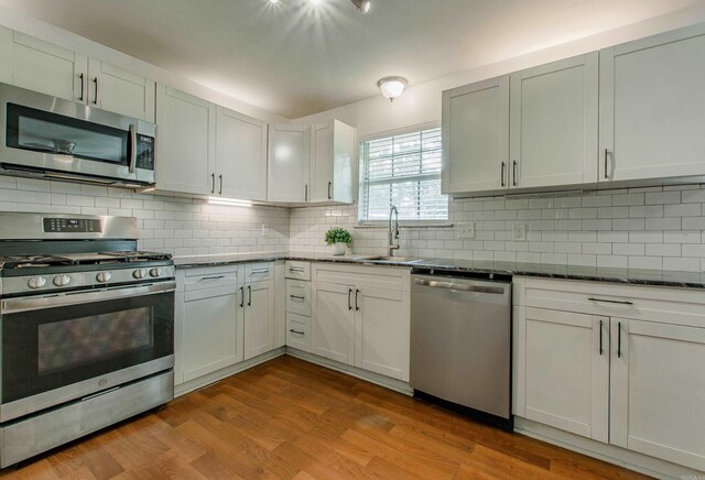 81 Stoneledge Dr, Maumelle, AR 72113 - kitchen featuring appliances with stainless steel finishes, backsplash, dark stone countertops, and wood finished floors