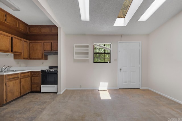 12605 Janelle Ct, Little Rock, AR 72205 - kitchen with white stove, under cabinet range hood, light countertops, brown cabinetry, and a skylight