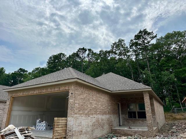 13423 Teton Dr, Little Rock, AR 72211 - view of side of home featuring brick siding, a garage, and roof with shingles