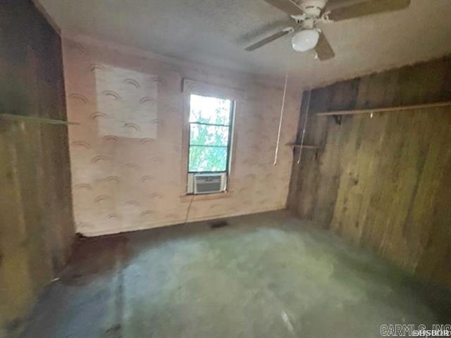 6430 Park Ave, Hot Springs, AR 71901 - unfurnished bedroom featuring wooden walls, unfinished concrete flooring, cooling unit, and ceiling fan