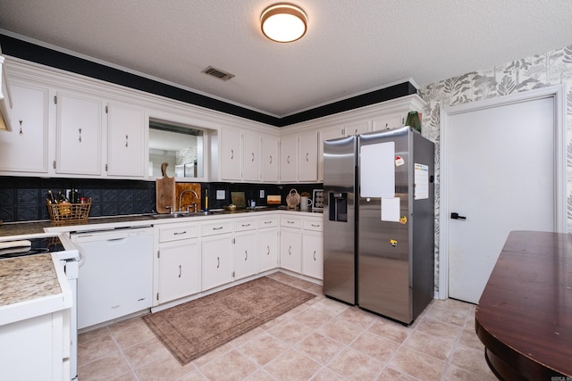 kitchen with white appliances, a textured ceiling, white cabinetry, decorative backsplash, and wallpapered walls