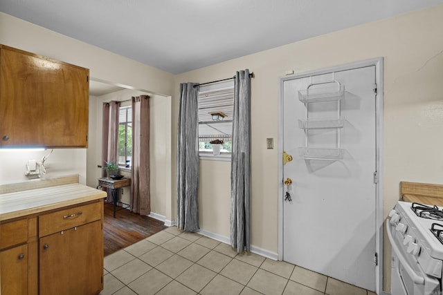 4005 W Berkley Dr, North Little Rock, AR 72118 - kitchen featuring white range with gas cooktop, light countertops, brown cabinetry, and light tile patterned flooring